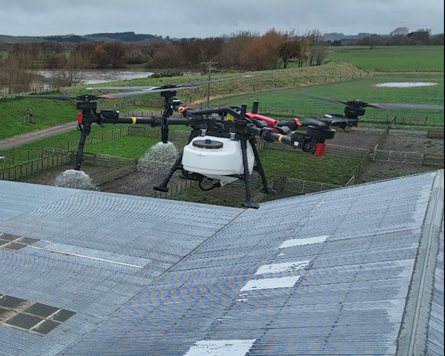 Spray drone treating moss strips on a large farm shed roof