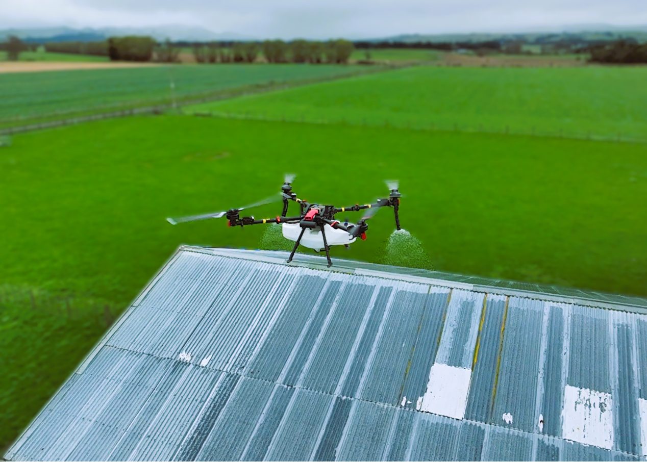 Spray drone treating a moss-covered farm shed roof